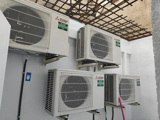 Tres acondicionadores de aire están apilados uno encima del otro en una pared.