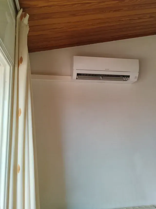 Una habitación con una ventana y un aire acondicionado montado en la pared.