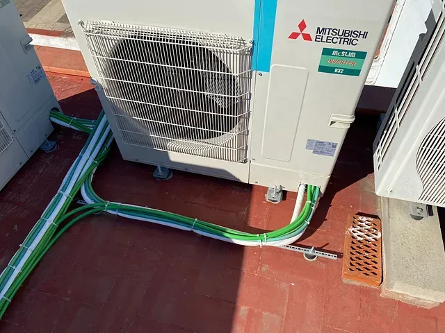 Un acondicionador de aire eléctrico Mitsubishi está colocado encima de un piso de ladrillos.
