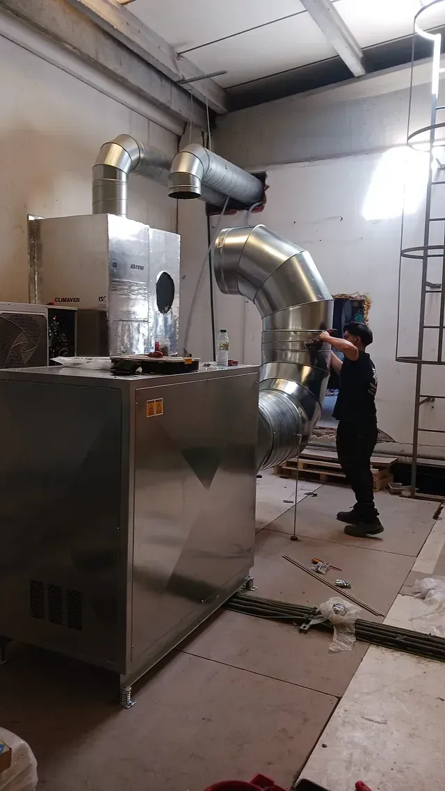 Un hombre está parado en una habitación con muchas tuberías.