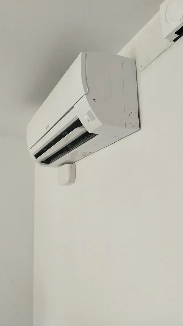Un acondicionador de aire blanco está colgado en una pared blanca.