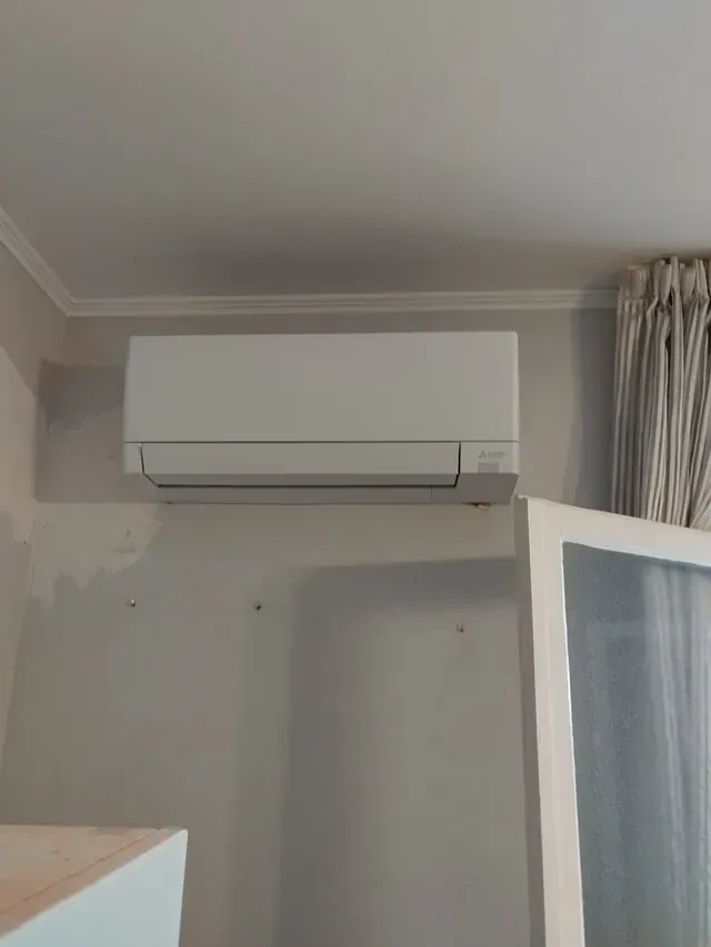 Un acondicionador de aire blanco cuelga del techo de una habitación.