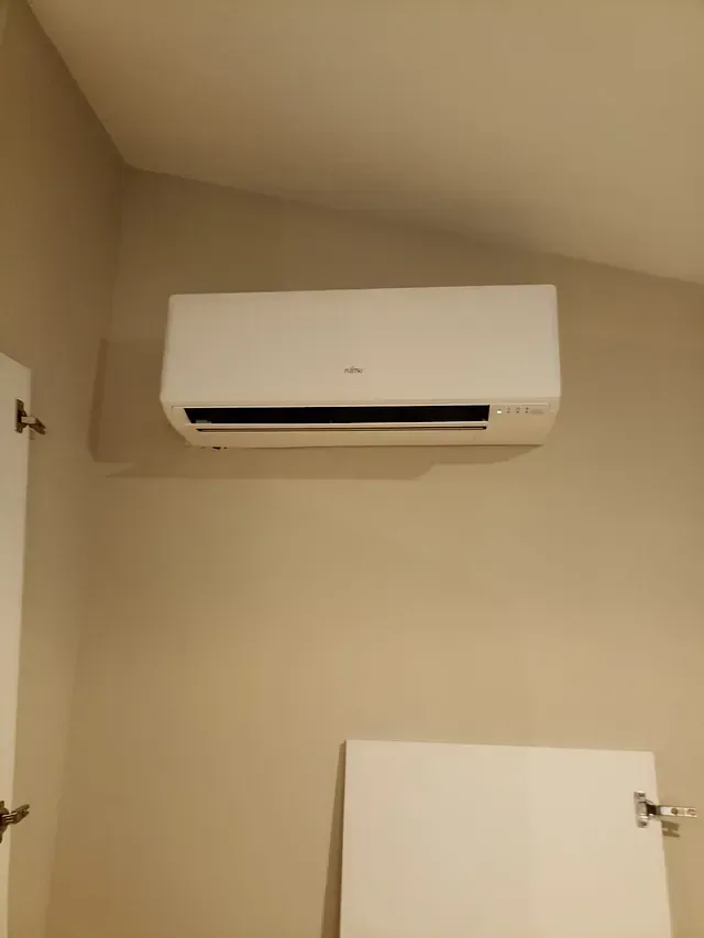 Un acondicionador de aire blanco cuelga del techo de una habitación.