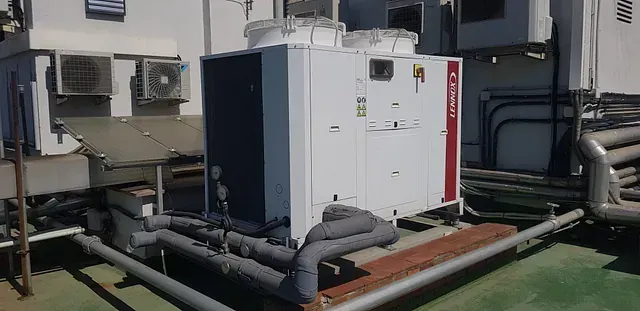 Una gran máquina blanca está sentada sobre un techo verde al lado de un edificio.