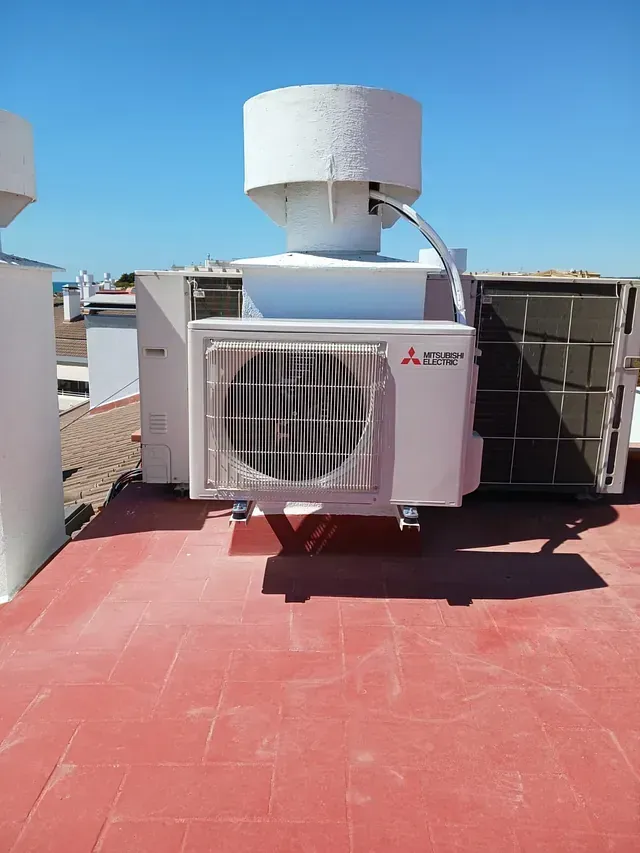 Un acondicionador de aire blanco está colocado encima de un piso de baldosas rojas.