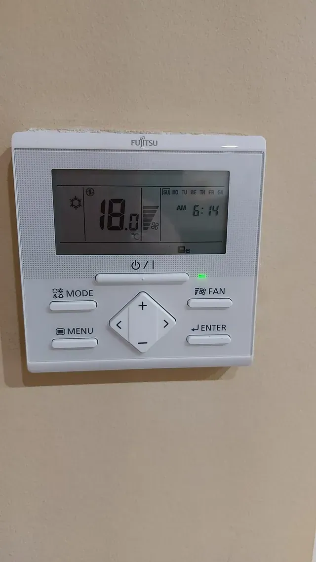 Un termostato digital está colgado en una pared.