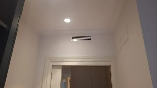 Un pasillo con una puerta y una luz en el techo.