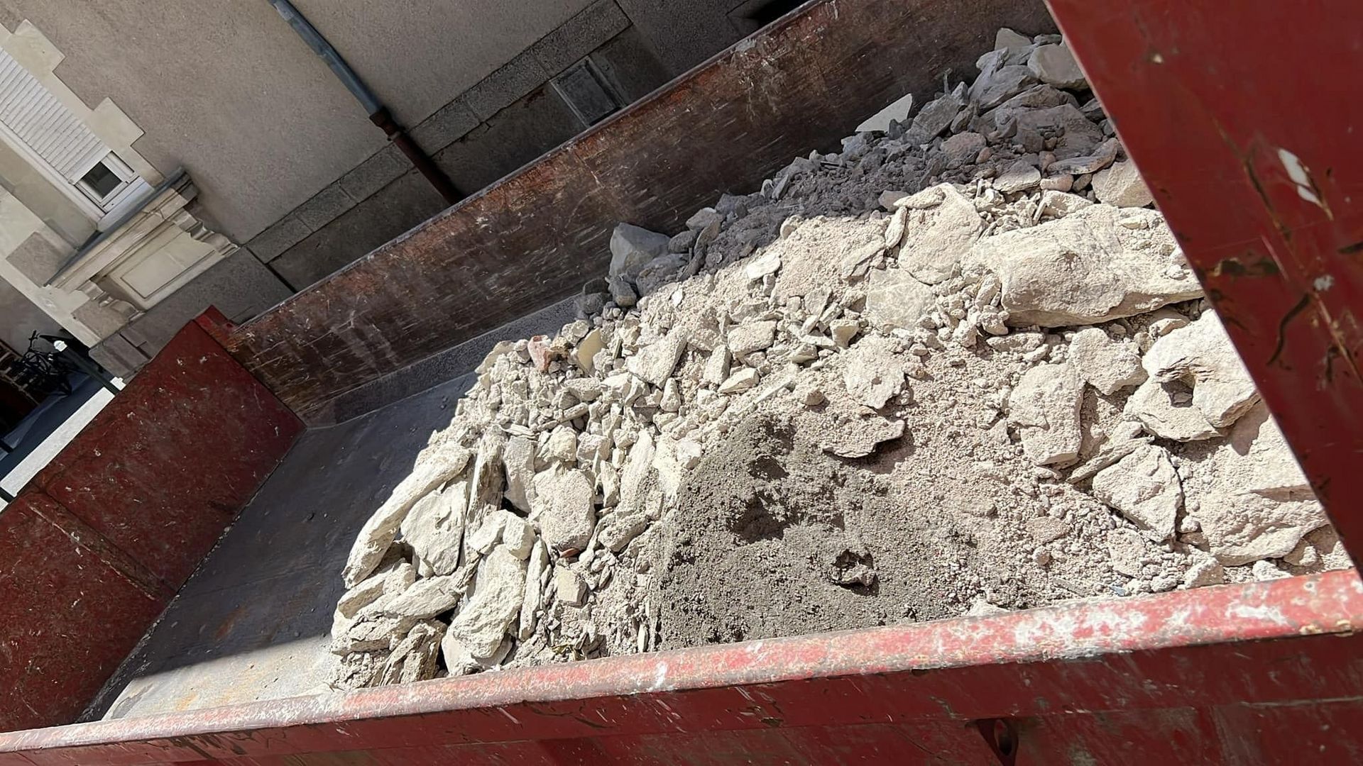 Benne rouge remplie de gravats de démolition