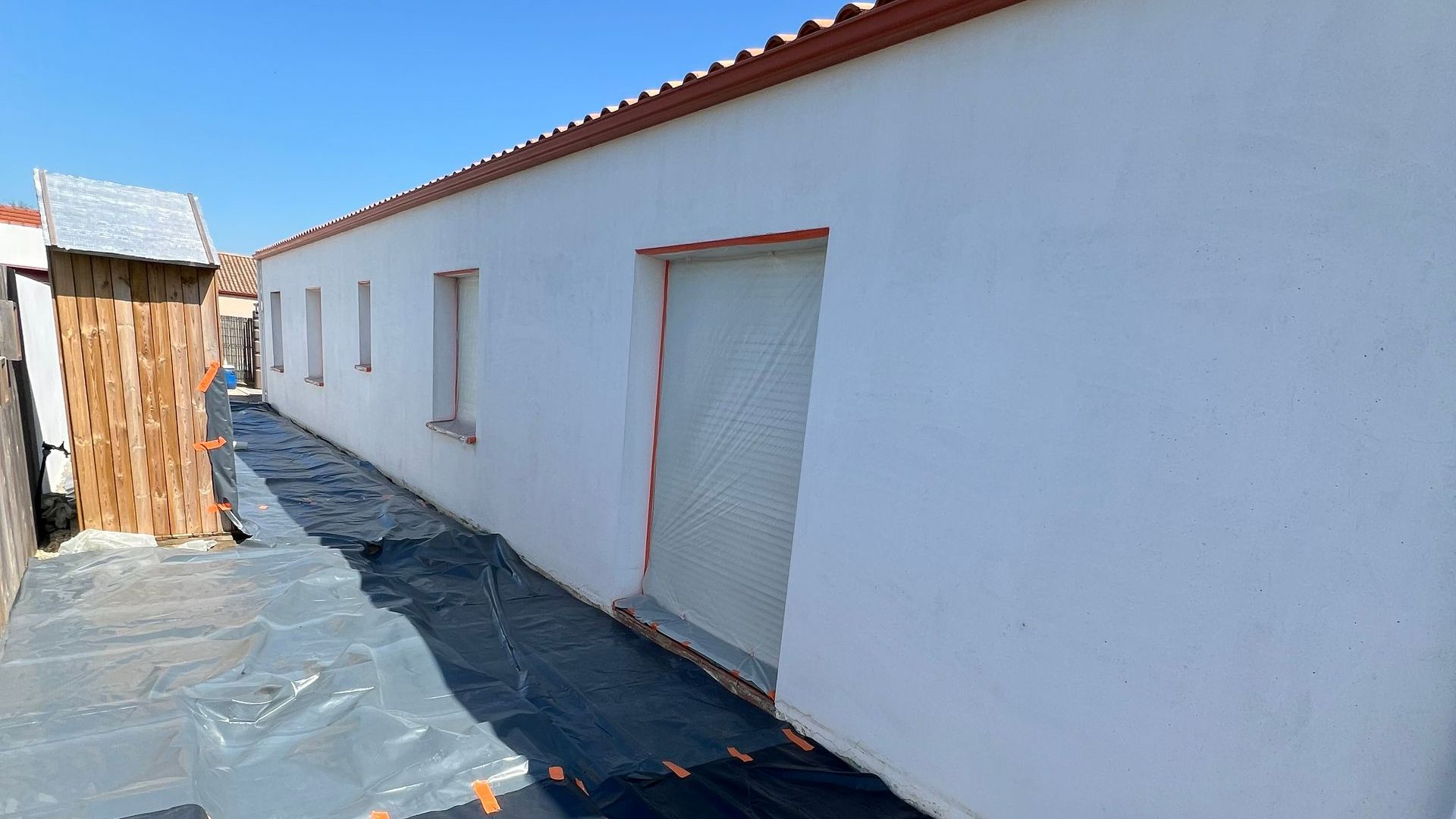 Jet de haute pression depuis un échafaudage pour nettoyer une façade couleur ocre