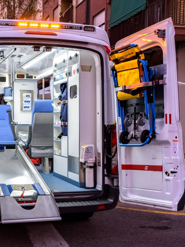 Arrière ouvert de l'ambulance ; intérieur avec équipement médical, civière et sièges.
