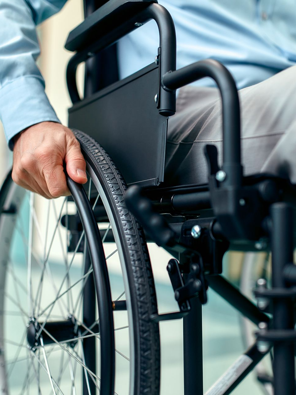 Personne en fauteuil roulant, main sur le volant, à l'intérieur.