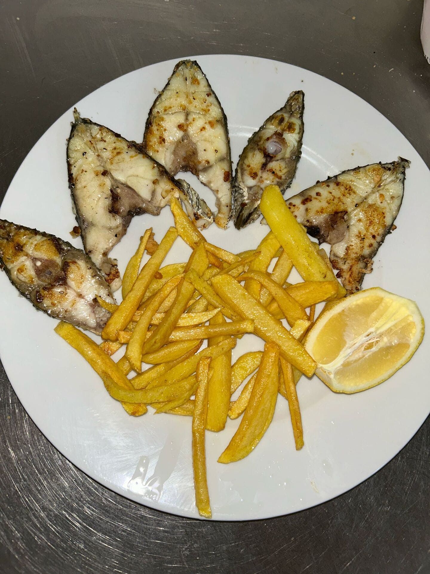 Un plato blanco cubierto con pescado y papas fritas.