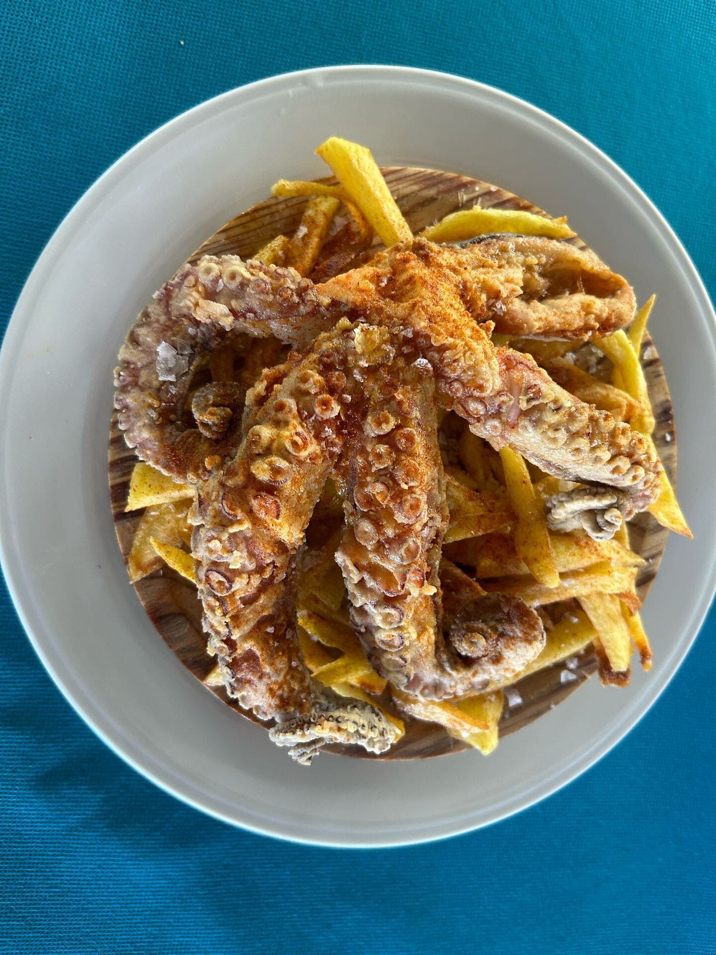 Un plato de comida con pulpo frito y patatas fritas en una mesa.