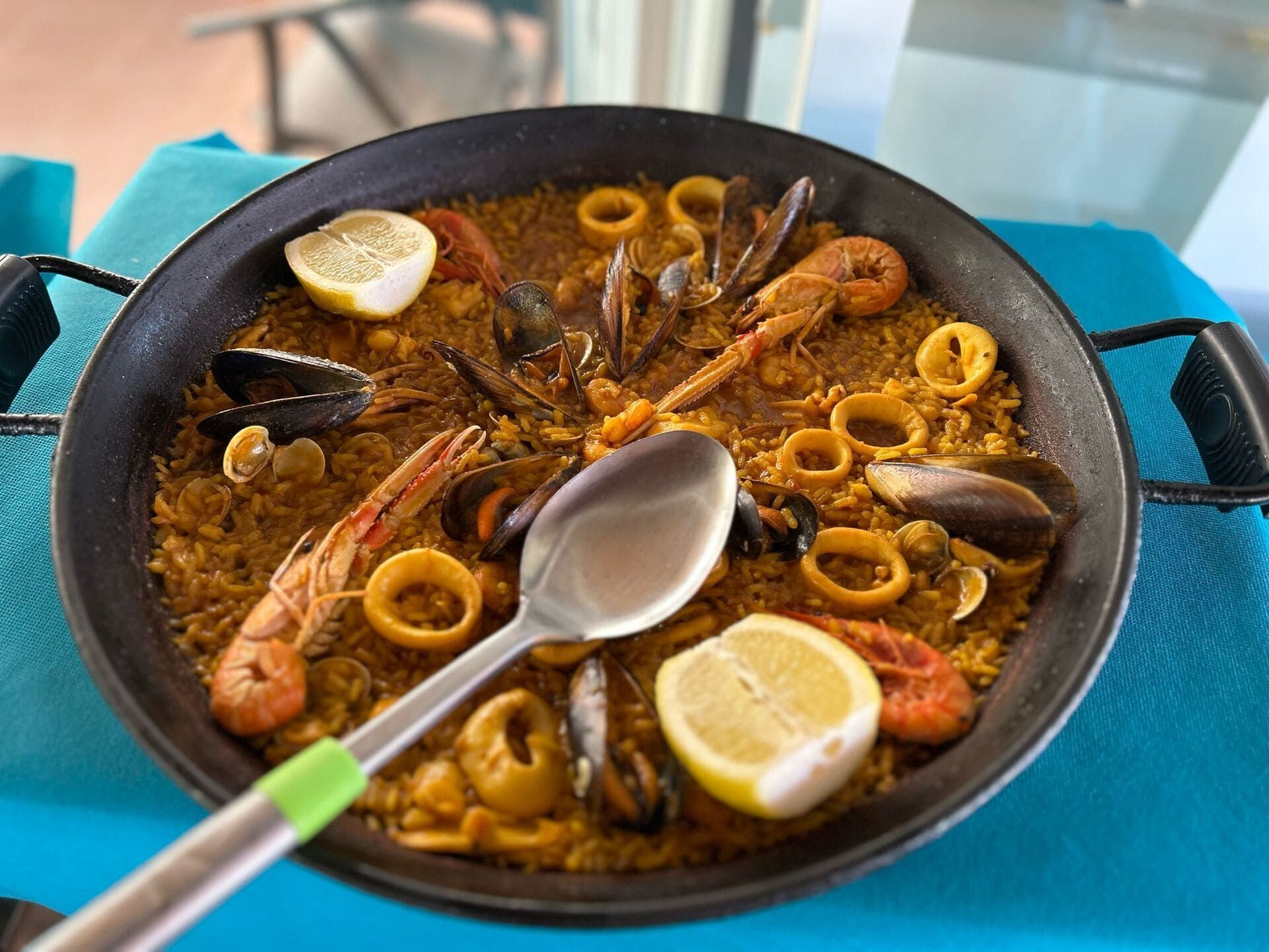 Una sartén de paella de mariscos con una cuchara dentro