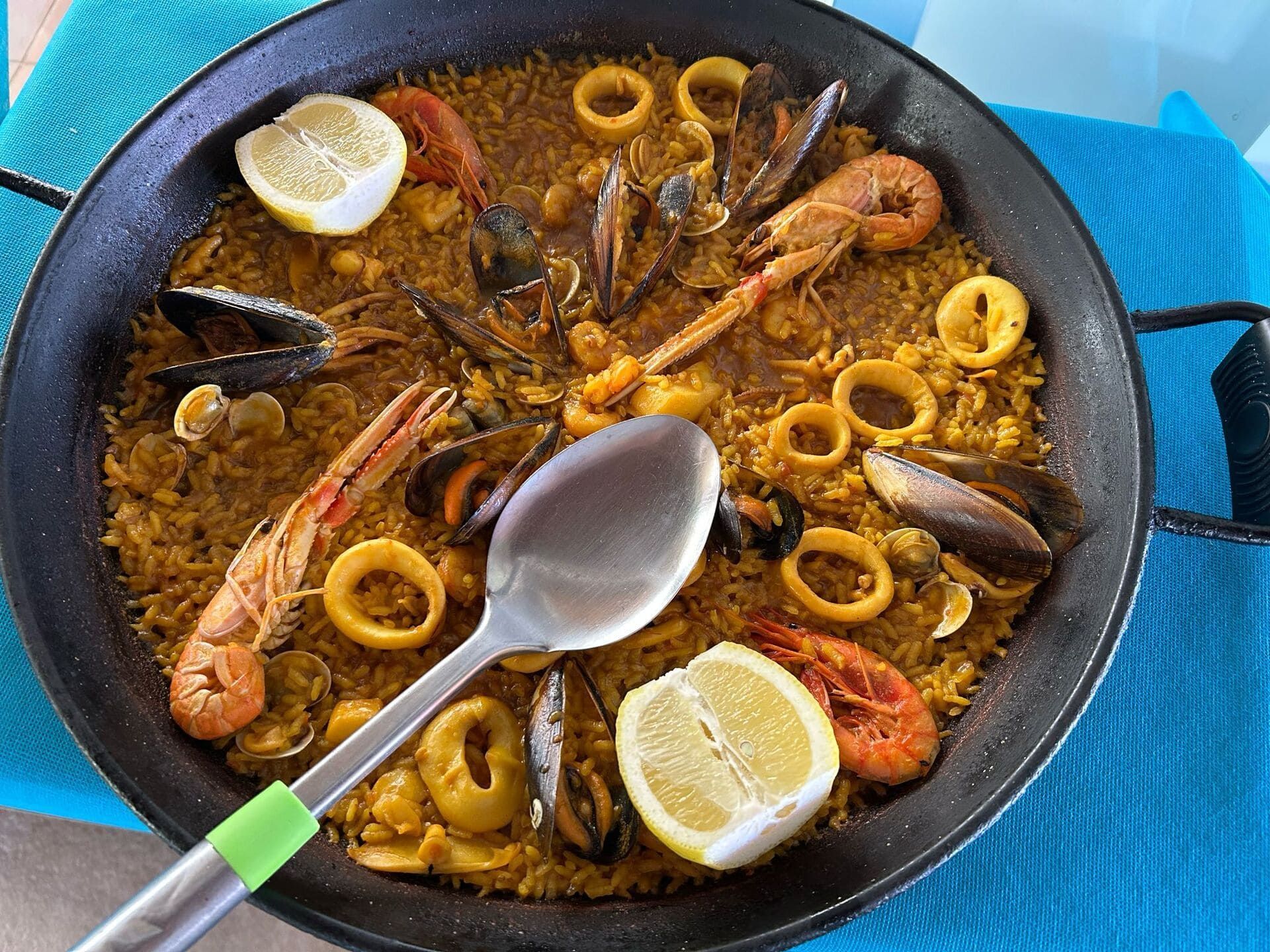 Una sartén de paella de mariscos con una cuchara dentro