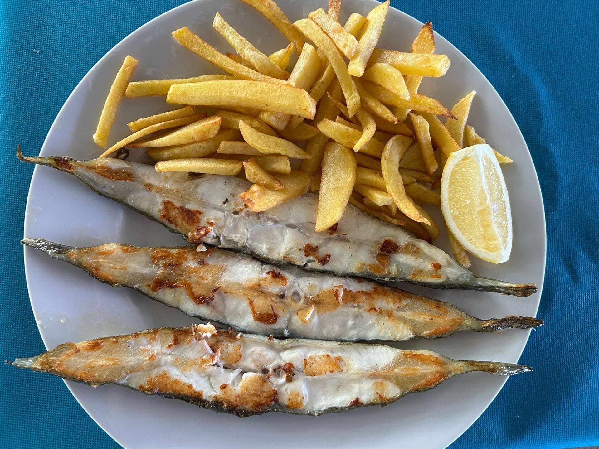 Un plato blanco cubierto con pescado y papas fritas sobre una mesa.