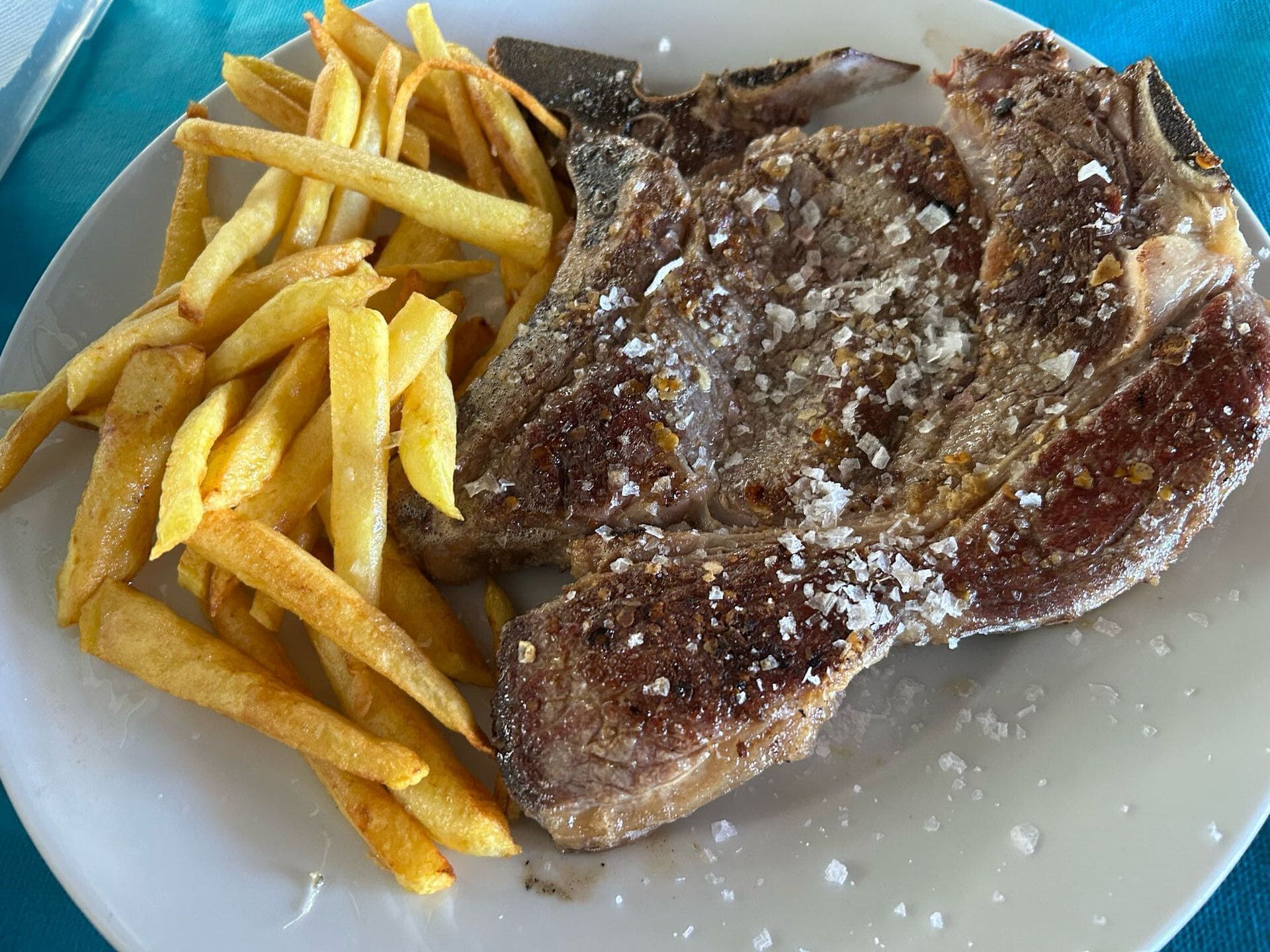 Un plato blanco cubierto con un filete y papas fritas.