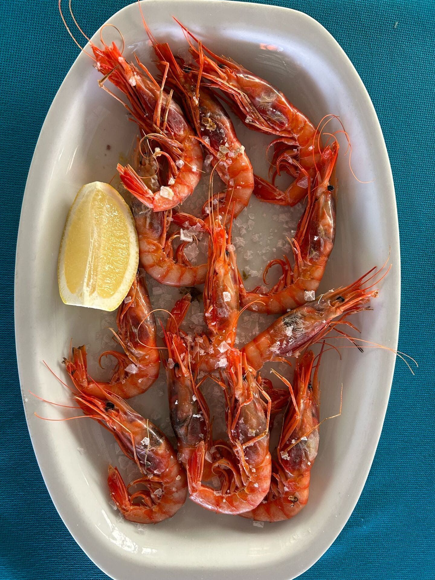 Un plato blanco cubierto con camarones y una rodaja de limón.