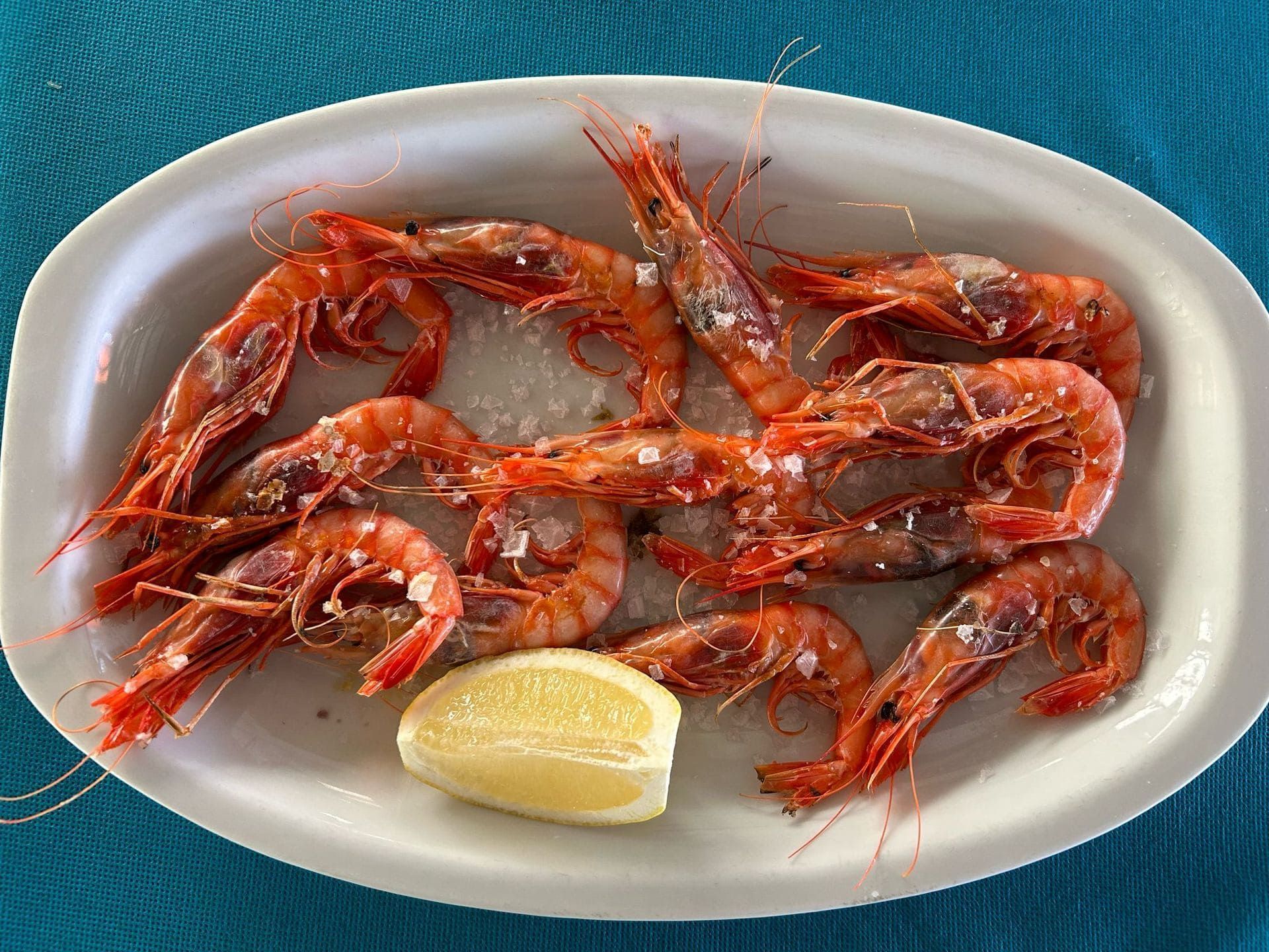 Un plato blanco cubierto con camarones y una rodaja de limón.