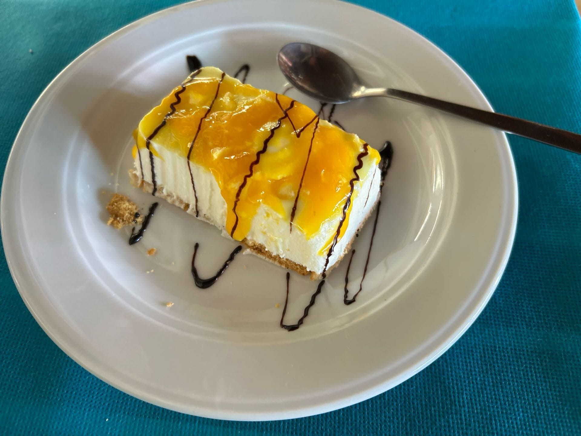 Un plato blanco cubierto con un trozo de tarta de queso y una cuchara.