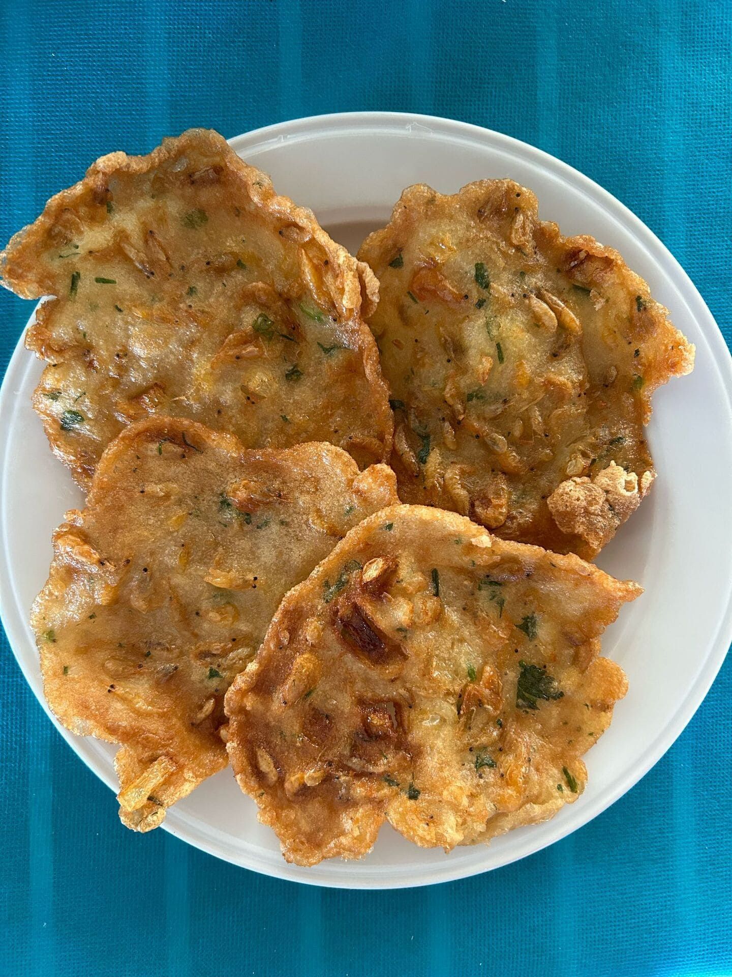 Un plato blanco cubierto de comida frita sobre un mantel azul.