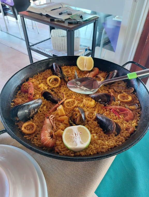 Una sartén de paella con mariscos y limones sobre una mesa.