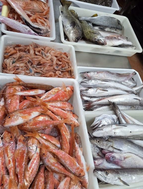 Varias bandejas de pescado y camarones están sobre una mesa.