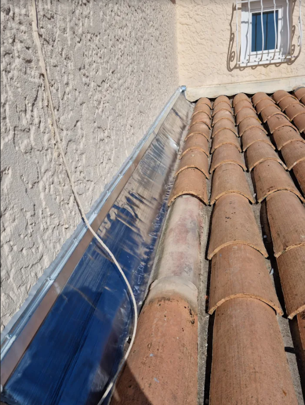 Faîtage en métal entre le mur vertical et la toiture en tuile