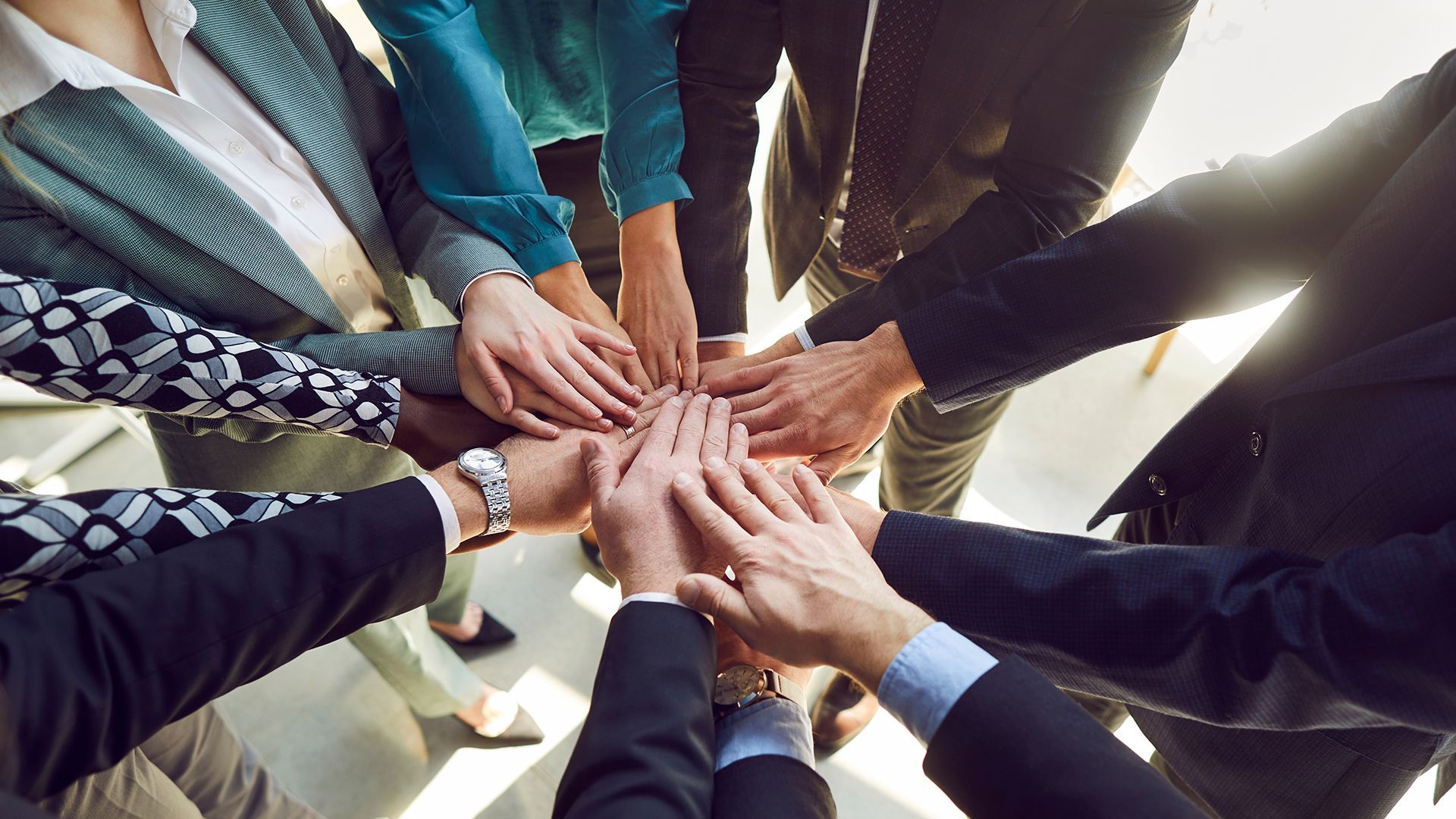 Grupo de personas con las manos juntas, simbolizando el trabajo en equipo.