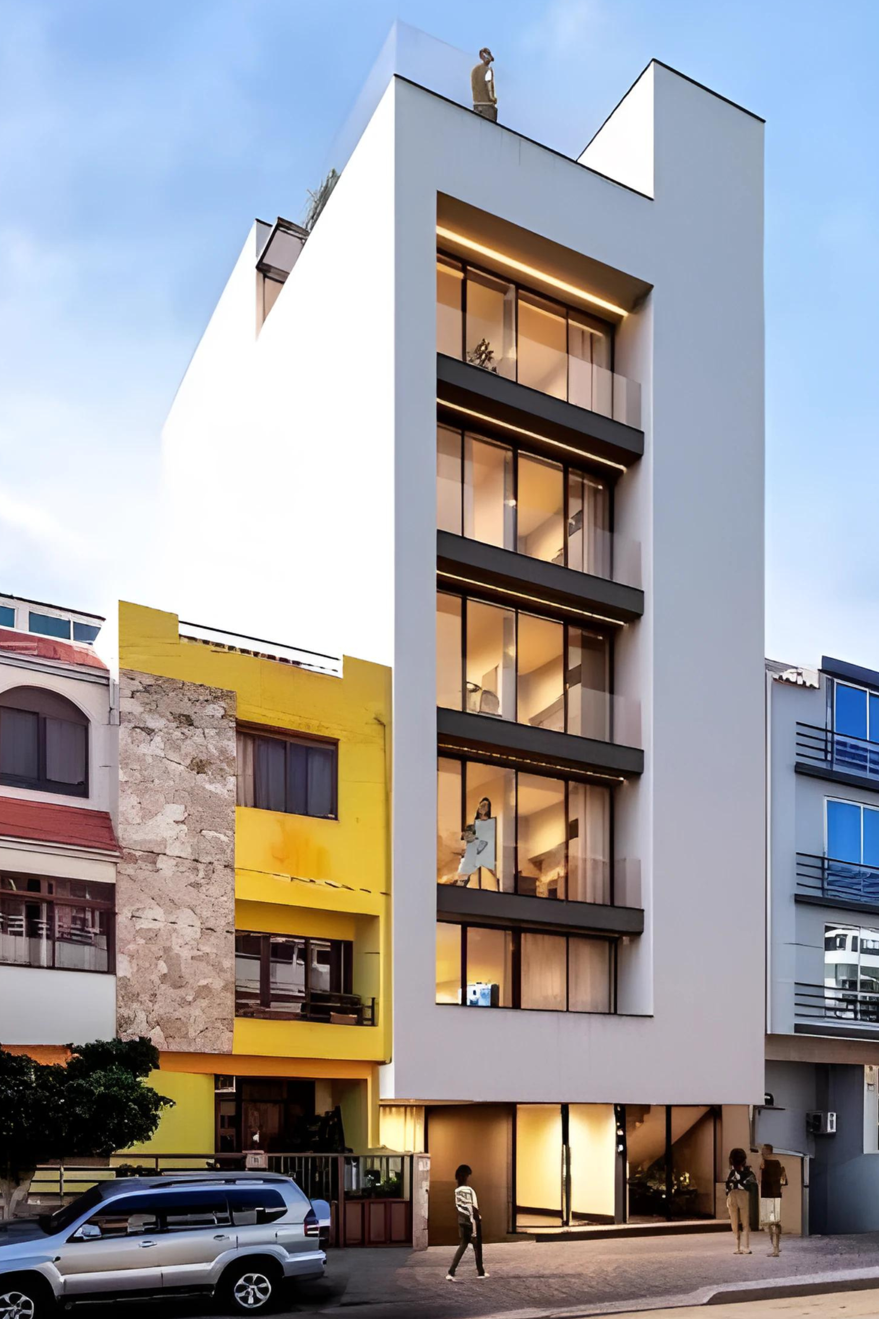 Prédio de apartamentos moderno e branco com grandes janelas e varandas, vista para a rua. Pessoas caminhando em frente.