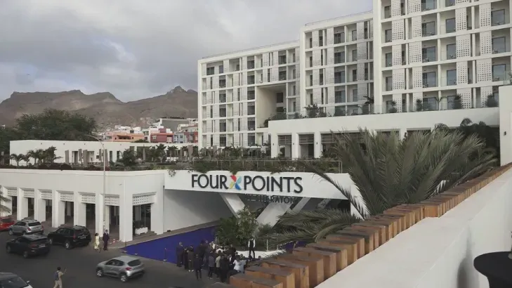 Um carro está passando por uma rua em frente a um prédio alto.