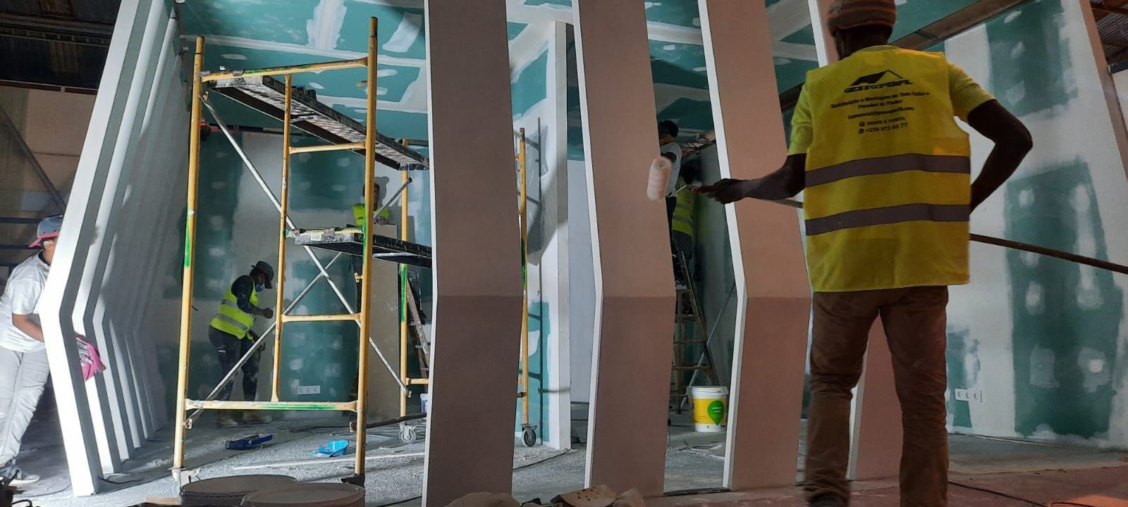 Um homem de colete amarelo está em uma sala em construção