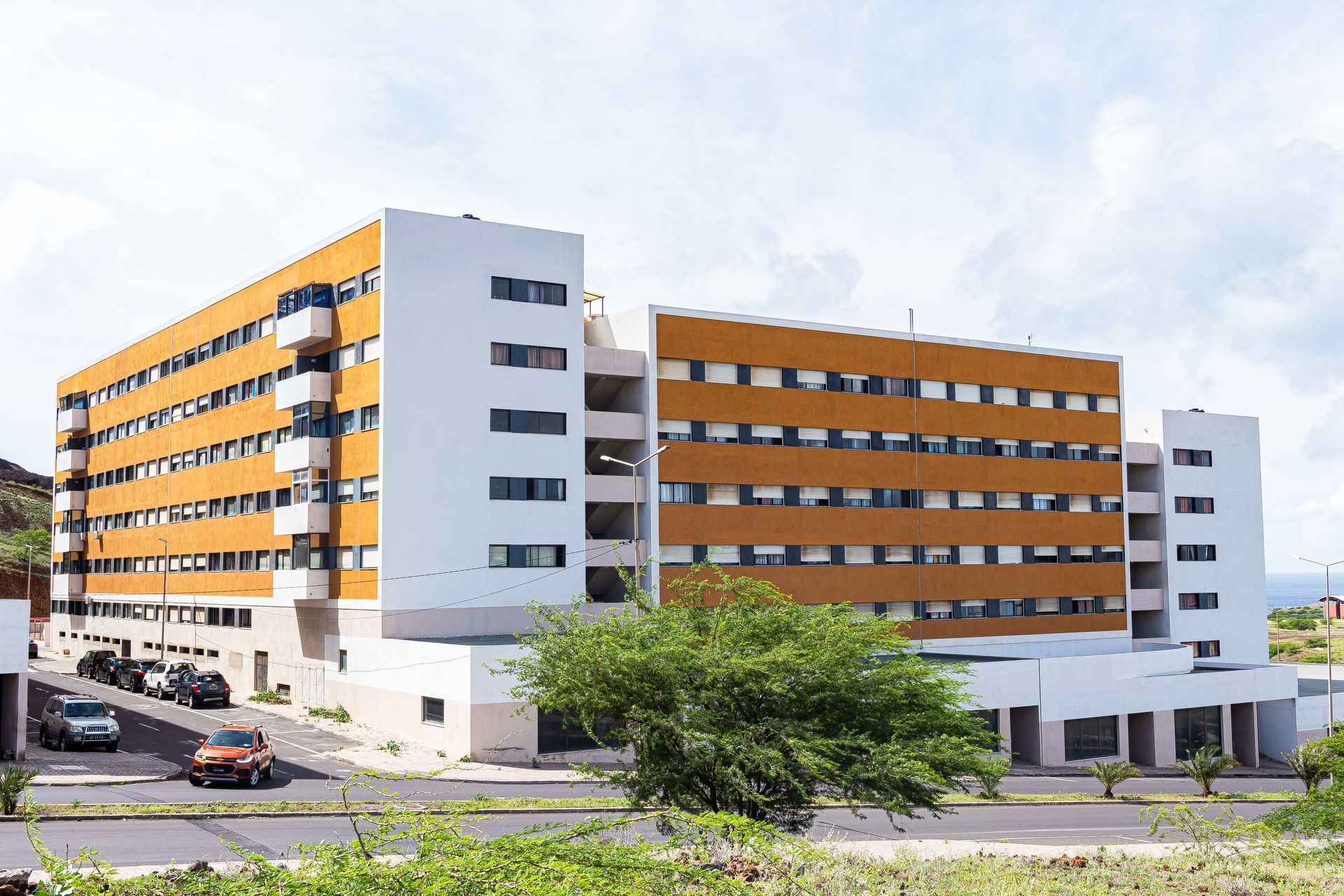 Um grande edifício branco e laranja com carros estacionados em frente