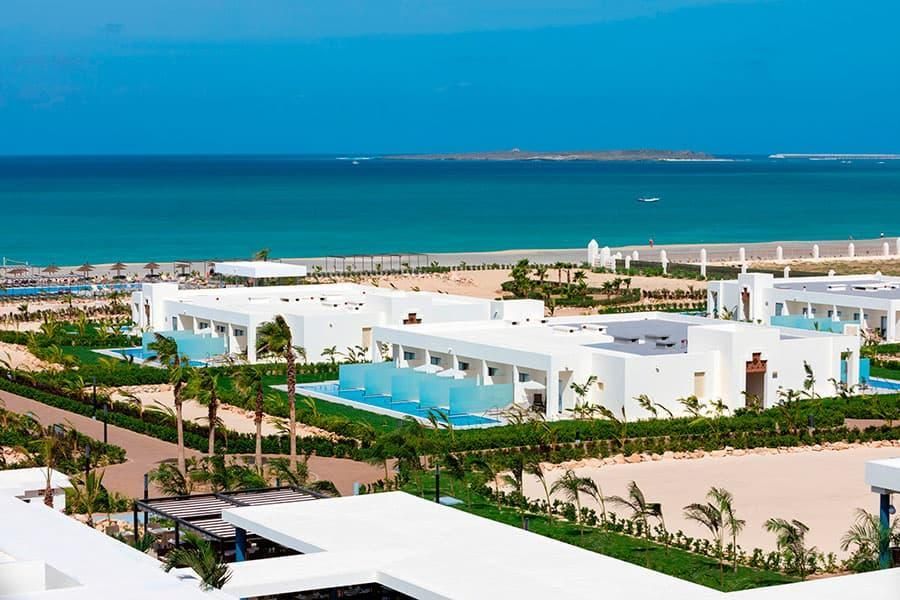 Um grande edifício branco com piscina em frente ao mar.