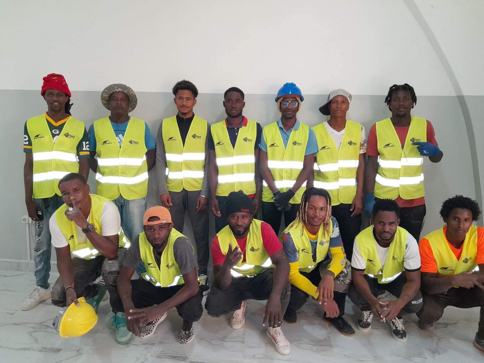 Um grupo de homens vestindo coletes amarelos e capacetes posam para uma foto