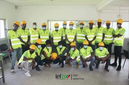 Um grupo de trabalhadores da construção civil usando capacetes e coletes posam para uma foto.