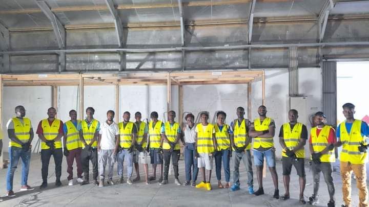 Um grupo de trabalhadores da construção civil posa para uma foto em um armazém.