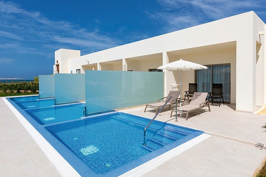 Uma grande casa branca com piscina em frente.