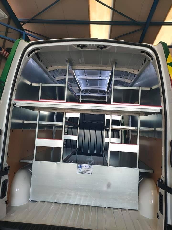 La parte trasera de una furgoneta con estantes y una escalera.