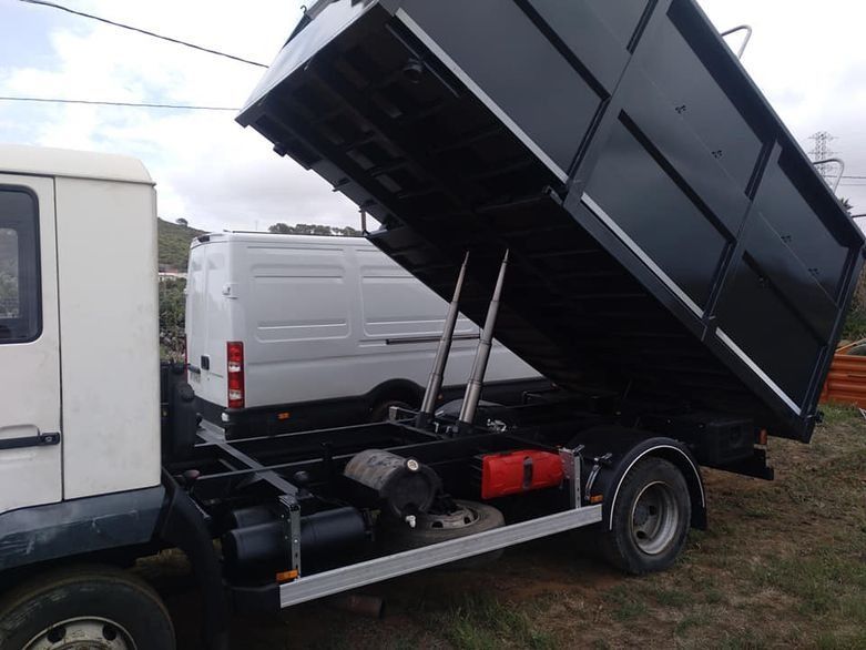 Una camioneta blanca está estacionada al lado de un camión volquete negro
