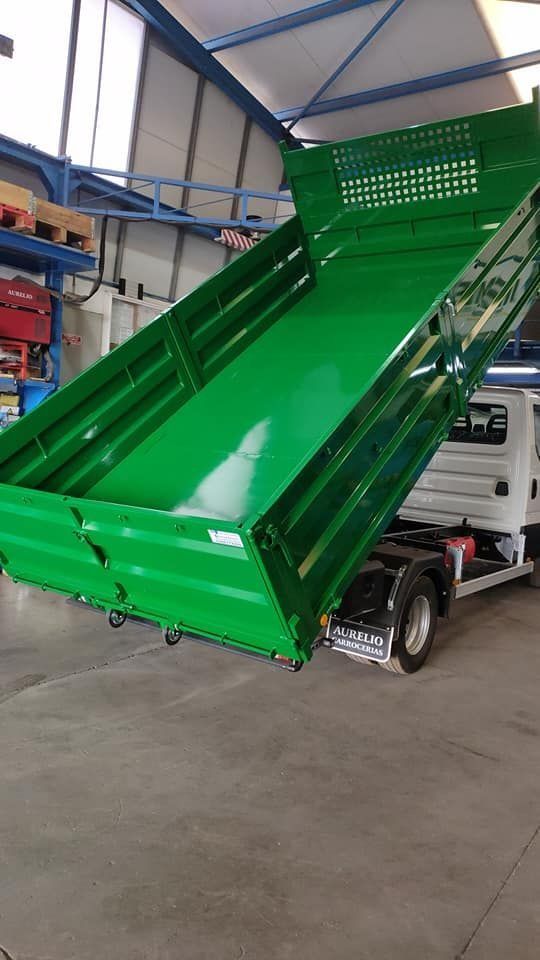 Un camión volquete verde está estacionado en un almacén.