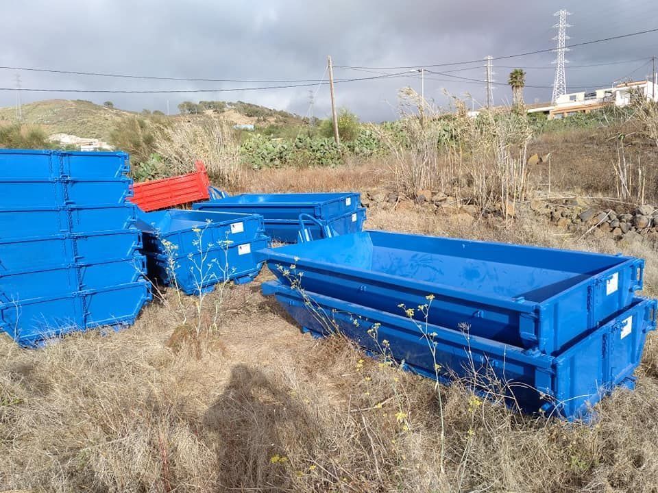 Un montón de contenedores de basura azules están apilados uno encima del otro en un campo.