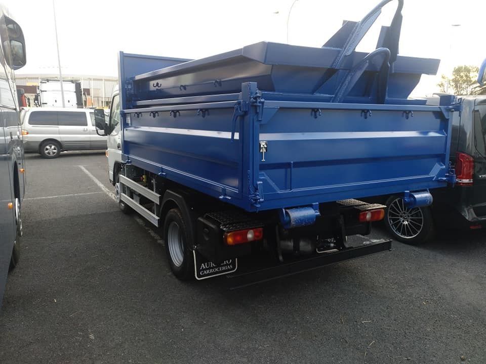Un camión volquete azul está estacionado en un estacionamiento