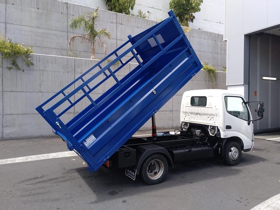 Un camión volquete azul está estacionado al costado de la carretera.
