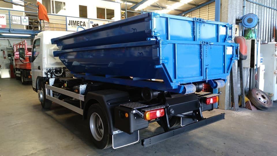 Un camión volquete azul está estacionado en un garaje.