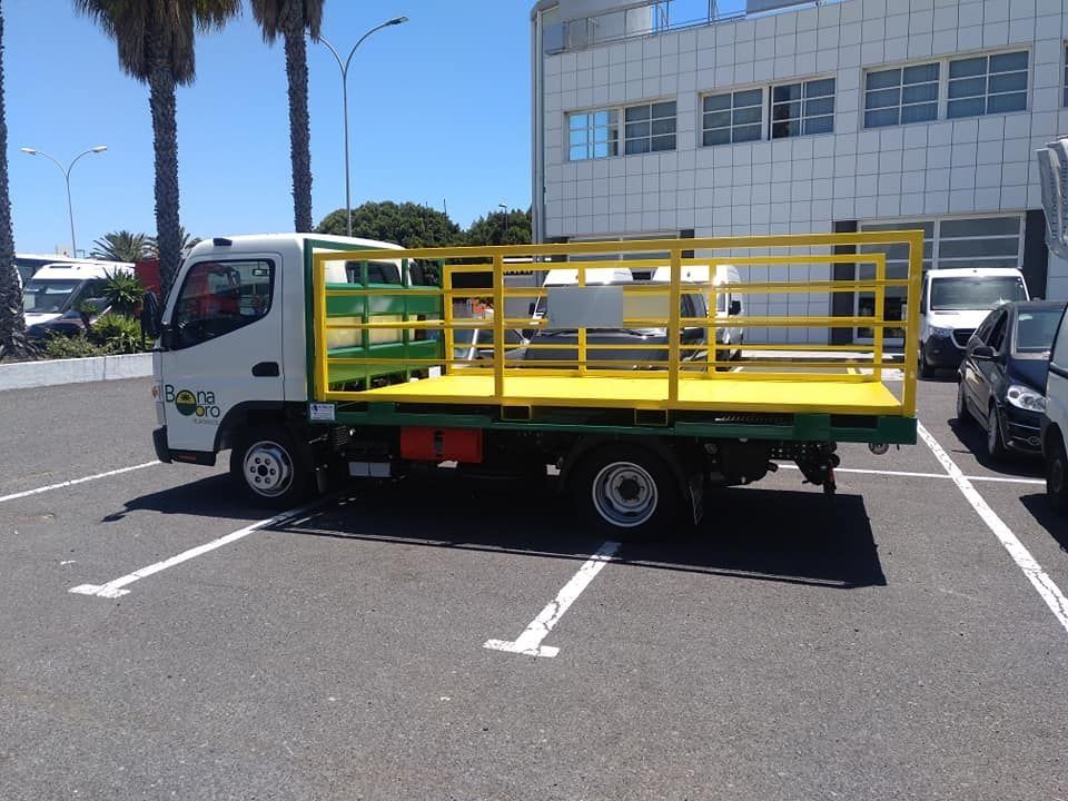 Un camión blanco con una jaula amarilla en la parte trasera está estacionado en un estacionamiento.