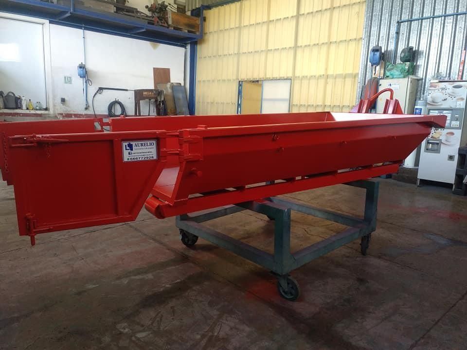 Un contenedor de basura rojo está sobre un carrito en una habitación.