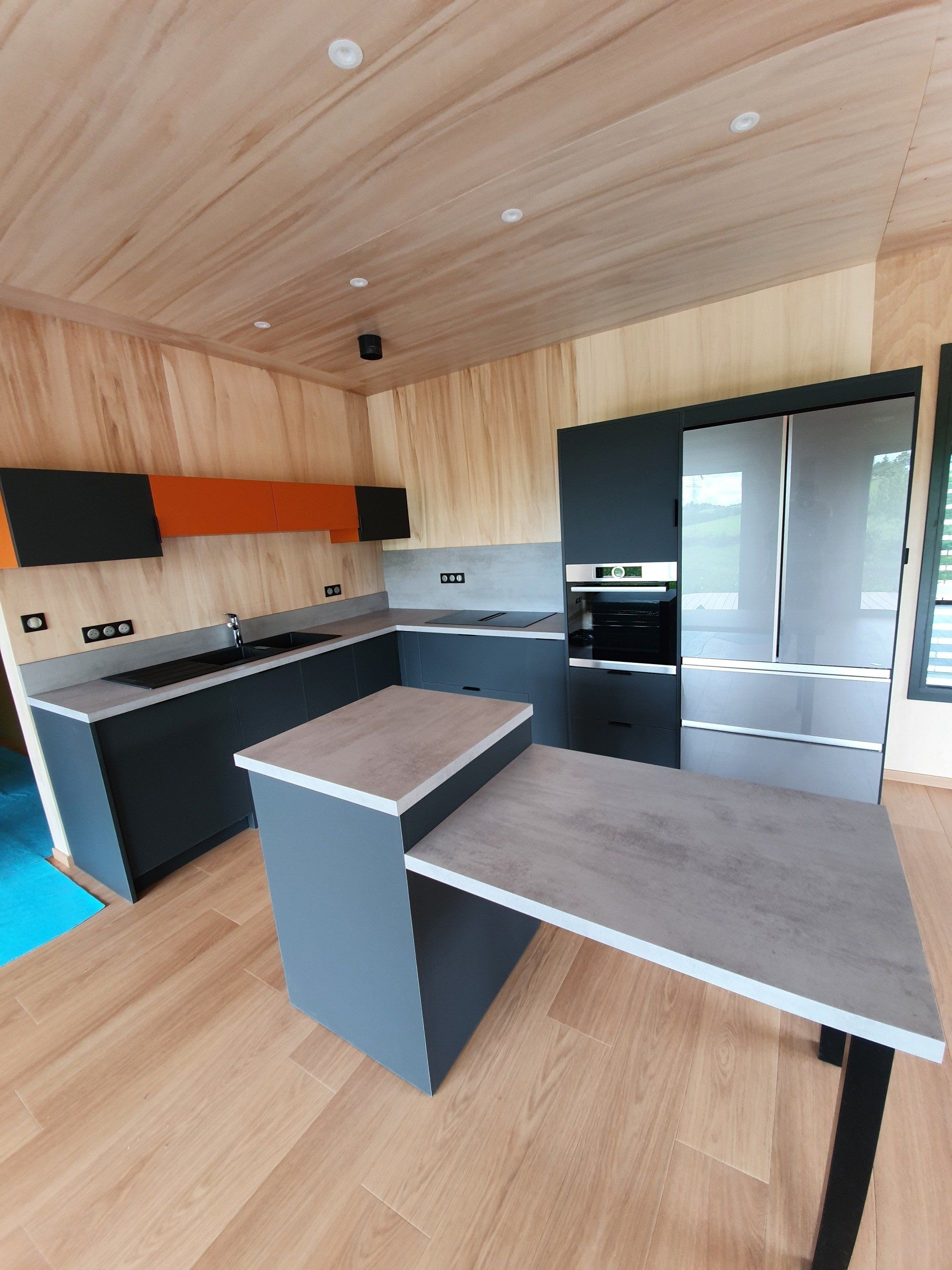 Cuisine moderne, bleue avec ilôt central et plan de travail effet béton ciré