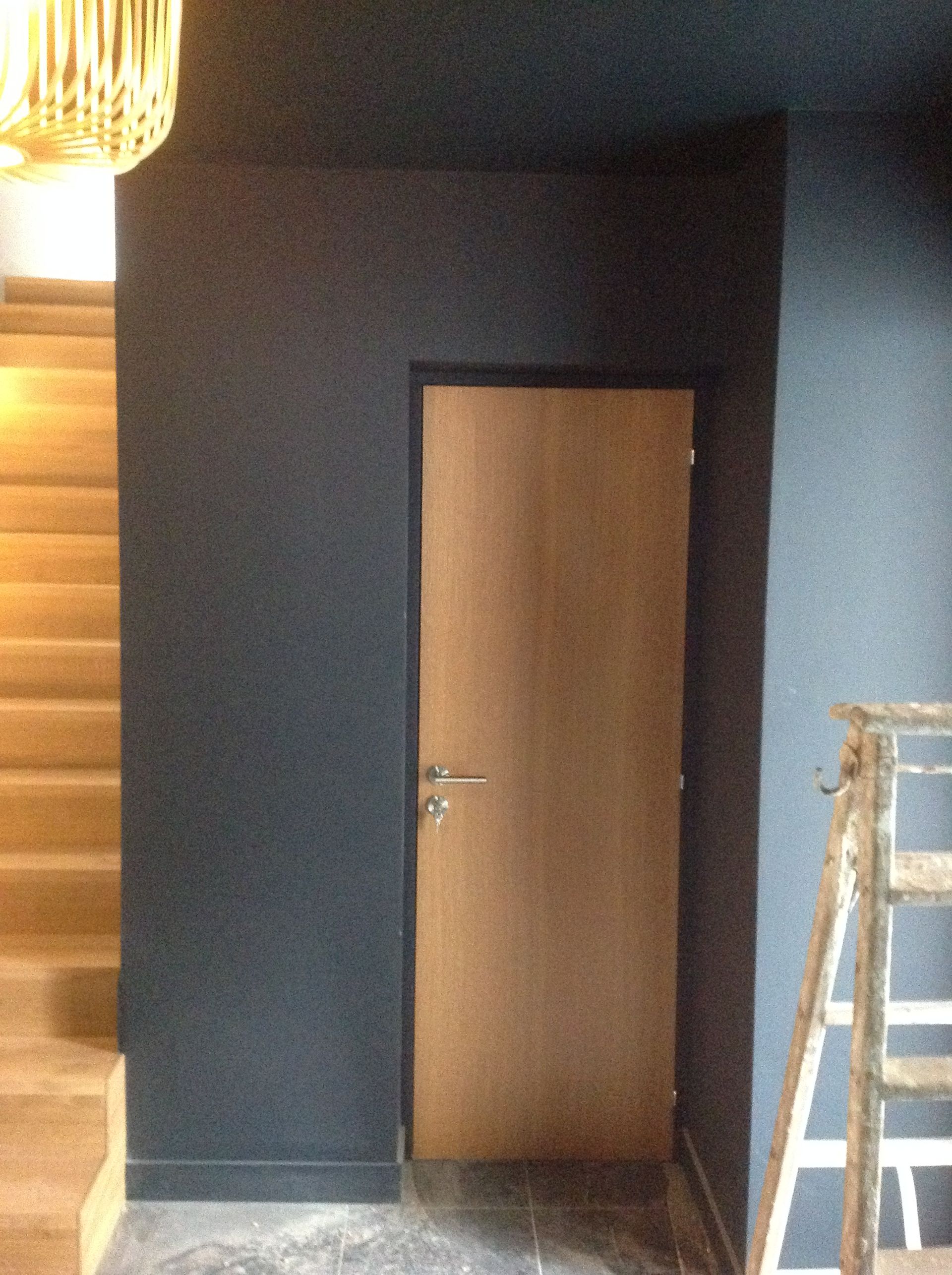 Porte intérieure avec revêtement stratifié, murs et plafond gris, escaliers en bois