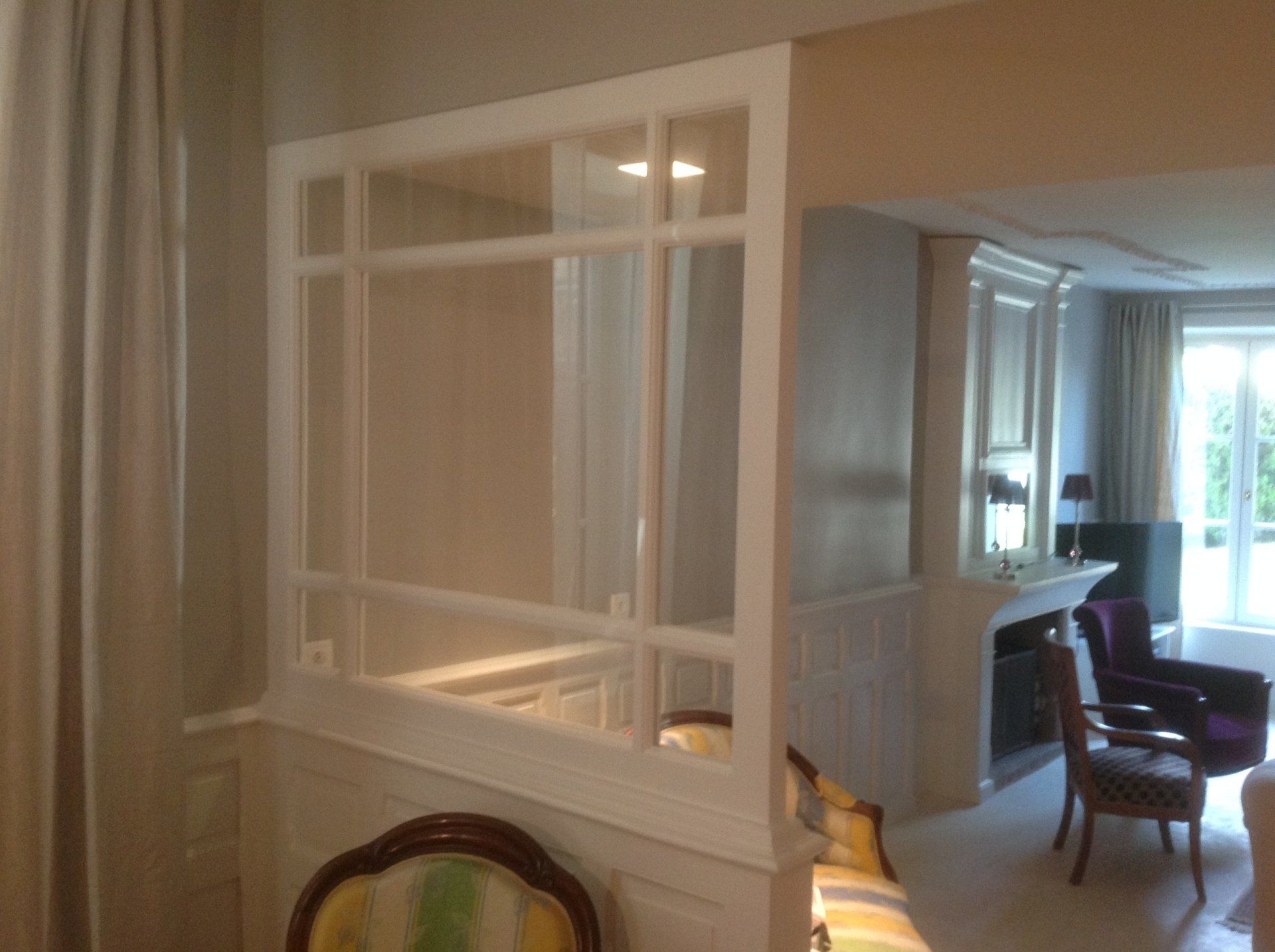 Cloison vitrée blanche avec armature en bois pour séparer un salon de la pièce adjacente